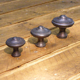 Cast iron embossed knob in 3 sizes 30mm, 35mm and 40mm arranged on a wooden background - ABC Ironmongery