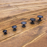 Cast iron plain round knob arranged on a wooden background showing all sizes from 20mm to 40mm diameter - ABC Ironmongery